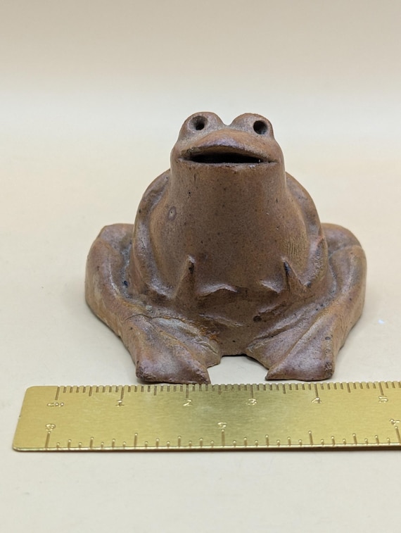 魅力的な小さな陶器のカエル。茶色の釉薬がかけられており、個性に