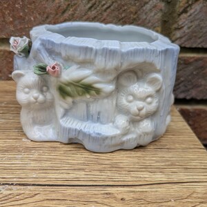 May include: A set of three ceramic canisters with lids. The canisters are white with a blue floral pattern. The largest canister is 20 cm tall, the medium is 18 cm, and the smallest is 15 cm.