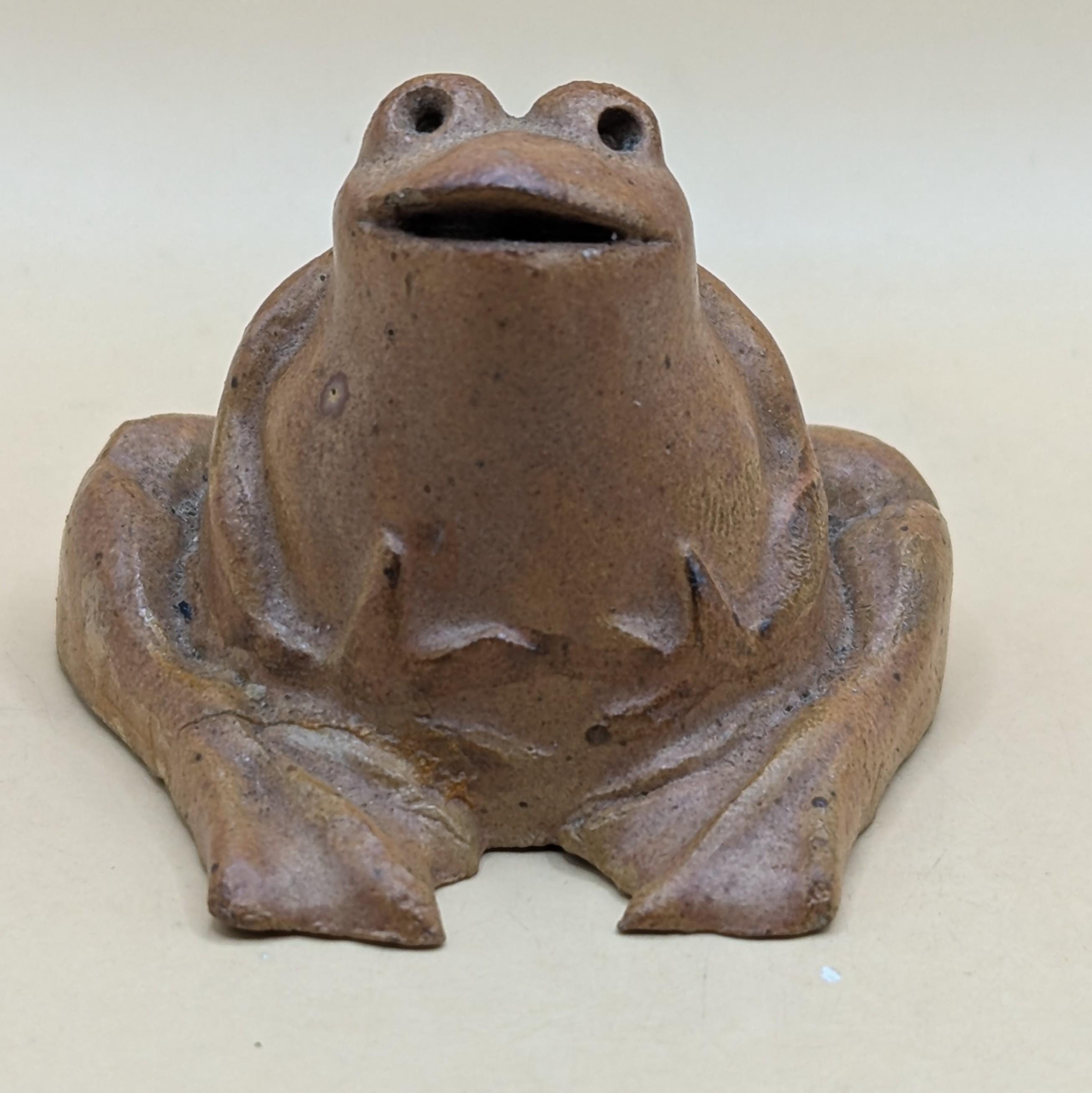 魅力的な小さな陶器のカエル。茶色の釉薬がかけられており、個性に