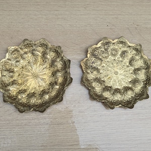 Puede incluir: Dos bandejas decorativas de metal de color dorado con intrincados diseños florales. Las bandejas son redondas y tienen un borde elevado.