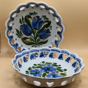 May include: Two white ceramic bowls with blue and yellow floral designs. The bowls have scalloped edges and openwork designs.