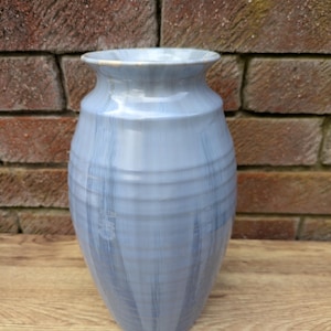 Op de afbeelding: Een lichtblauwe keramische vaas met een textuur, gestreept ontwerp. De vaas heeft een ronde bodem en een licht uitlopende opening.