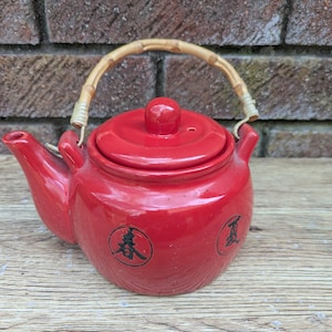 Bule de chá pequeno em cerâmica vermelha estilo japonês vintage dos anos 70 com alça de bambu e motivos de personagens asiáticos.