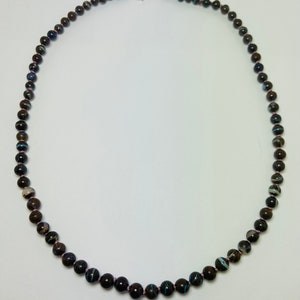 May include: A necklace made of dark brown, blue, and white patterned beads with a silver clasp.