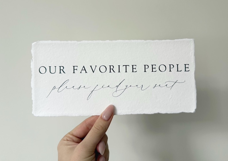 May include: White sign with the text "OUR FAVORITE PEOPLE please find your seat" in black lettering.