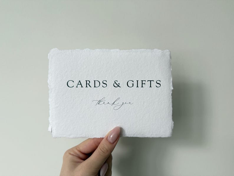 May include: A white card with the text "CARDS & GIFTS" in black lettering and "thank you" in cursive handwriting.