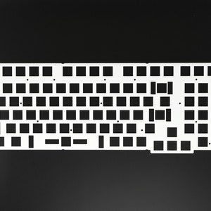 May include: White plastic keyboard plate with cutouts for keys. The plate is designed for a full-sized keyboard layout.