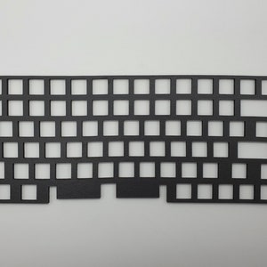 May include: Black plastic keyboard plate with cutouts for key switches. The plate is designed for a 60% keyboard layout.