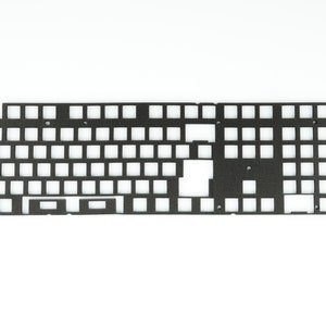 Puede incluir: Una placa de teclado de metal negro con recortes para interruptores de teclas. La placa está diseñada para una disposición de teclado del 60%.