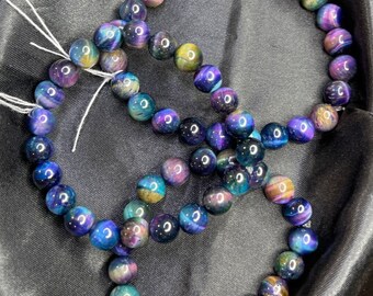 May include: Two bracelets made of round, iridescent blue, purple, and gold tiger's eye beads.