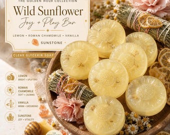 May include: A collection of round, translucent yellow glycerin soap bars with sunflower-shaped imprints, arranged on a wooden tray with dried chamomile flowers, sage bundles, and orange slices. The label reads The Golden Hour Collection Wild Sunflower Joy + Play Bar Lemon Roman Chamomile Vanilla Sunstone Clear Glycerin Soap.