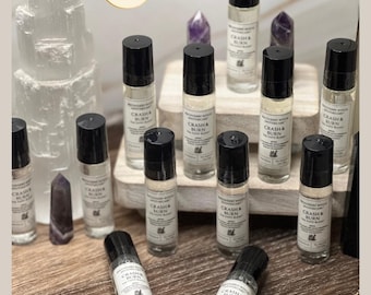 May include: A collection of clear glass roller bottles with black caps, each featuring a white label printed with the text The Recovery Witch Apothecary and Crash & Burn The Fapo Blend. The bottles are arranged alongside several crystal points.