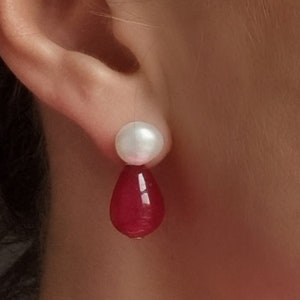 May include: A pair of earrings with a white pearl top and a teardrop-shaped red gemstone bottom.