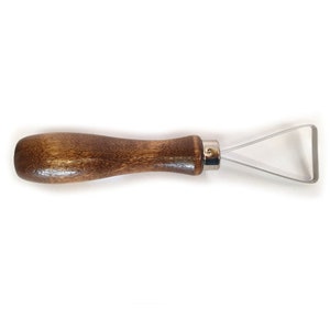 May include: A wooden handled sculpting tool with a triangular blade. The tool is made of metal and wood.
