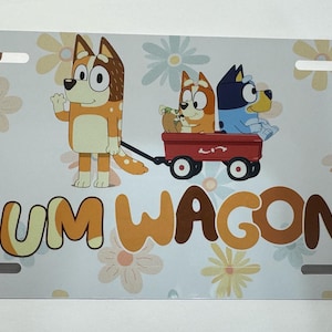 May include: White license plate with the text "MUM WAGON!" and a cartoon image of three dogs in a red wagon. The background features a floral pattern with light blue and yellow flowers.