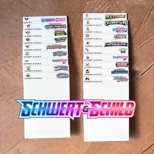 Peut inclure: Deux s&eacute;parateurs rectangulaires blancs pour cartes &agrave; collectionner, chacun pr&eacute;sentant une colonne de logos imprim&eacute;s et le texte Schwert & Schild. Les logos repr&eacute;sentent diverses extensions, dont Base Set, Clash der Rebellen, et d'autres, avec le logo Schwert & Schild en bas.