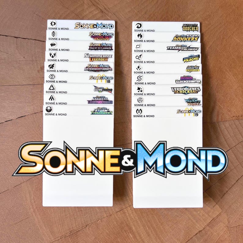 Peut inclure: Deux s&eacute;parateurs en plastique blanc rectangulaires pour le rangement de cartes &agrave; collectionner, chacun pr&eacute;sentant une colonne d'&eacute;tiquettes imprim&eacute;es avec le texte Sonne & Mond, divers logos d'extension et des titres comme Nacht in Flammen.