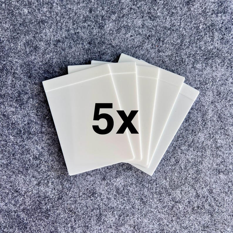 Peut inclure: Un ensemble de cinq cartes rectangulaires en plastique blanc dispos&eacute;es en &eacute;ventail. Les cartes ont une finition lisse et opaque avec une surface plane et propre. Le texte 5x est imprim&eacute; en police noire grasse au centre de la carte sup&eacute;rieure.