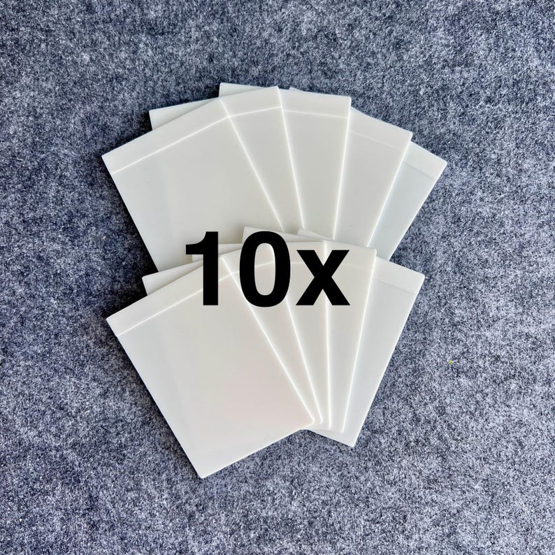 Peut inclure: Un ensemble de dix cartes rectangulaires en plastique blanc dispos&eacute;es en &eacute;ventail. Chaque carte pr&eacute;sente une surface lisse et opaque avec un design aux bords nets. Le texte noir en gras "10x" est centr&eacute; sur les cartes superpos&eacute;es.