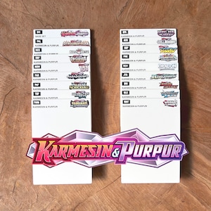 Peut inclure: Deux s&eacute;parateurs rectangulaires blancs pour cartes &agrave; collectionner, chacun pr&eacute;sentant une liste d'abr&eacute;viations et de logos de s&eacute;ries. Le grand logo en bas indique Karmesin & Purpur. Le texte inclut divers noms de s&eacute;ries comme Base Set, 151 et Paradox Rift.