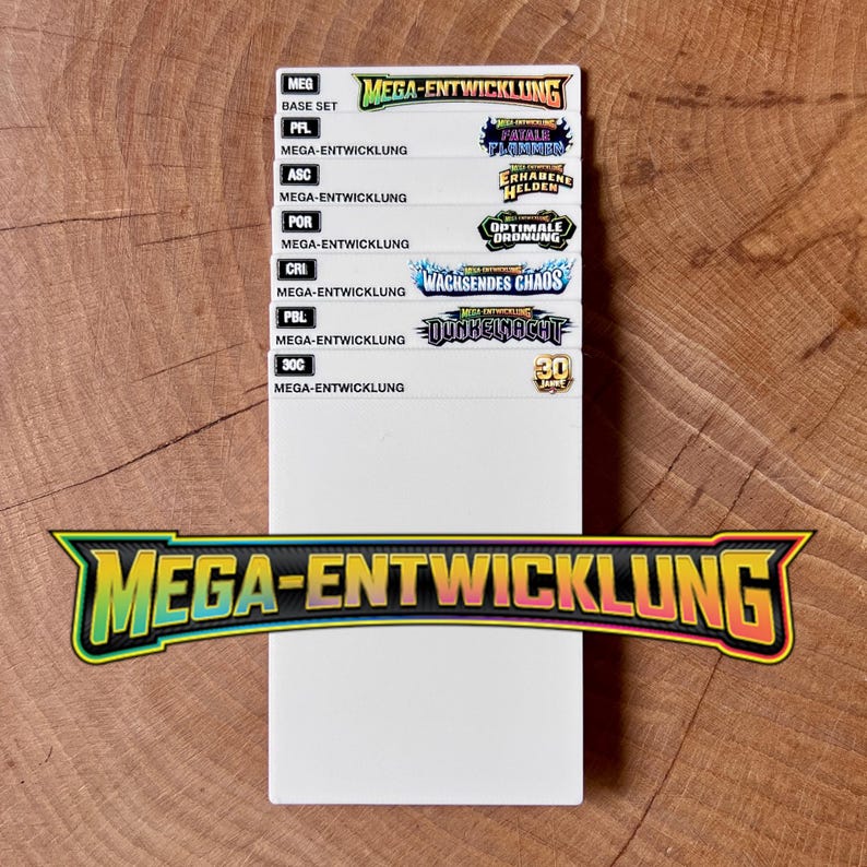 Peut inclure: Une carte rectangulaire blanche pr&eacute;sentant une liste d'&eacute;tiquettes Mega-Entwicklung, notamment Base Set, Fatale Flammer, Erhabene Helden, Optimale Ordnung, Wachsendes Chaos, Dunkelnacht et 30 Jahre. Le texte Mega-Entwicklung appara&icirc;t en grand.