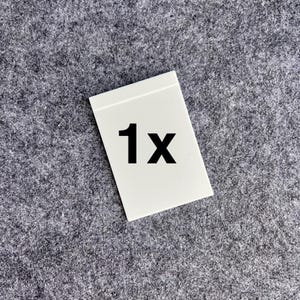 Peut inclure: Une carte rectangulaire blanche pr&eacute;sentant le texte noir en gras 1x centr&eacute; sur sa surface. La carte poss&egrave;de une finition lisse et plate avec des bords droits et nets, offrant un indicateur visuel clair et simple pour la quantit&eacute;.