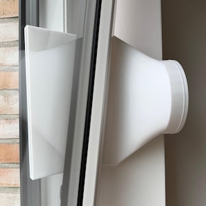 May include: A white plastic window seal adapter for a portable air conditioner hose. The device features a flat, rectangular mounting plate attached to a tapered, cylindrical nozzle that extends outward, designed to fit into a window frame.