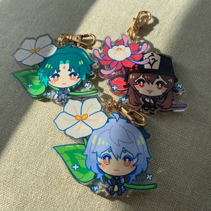 Puede incluir: Tres encantos de personajes de anime coloridos con dise&ntilde;os florales. Cada encanto presenta un personaje diferente con una expresi&oacute;n &uacute;nica y un dise&ntilde;o floral. Los encantos est&aacute;n hechos de acr&iacute;lico transparente y tienen un anillo de metal dorado para sujetar a un llavero o bolso.