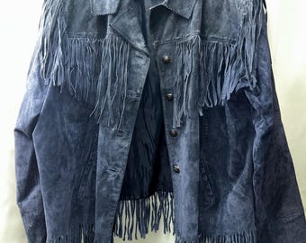 May include: A dark blue suede jacket featuring long fringe detailing across the chest, shoulders, and hemline. The jacket includes a classic collar, a button-front closure with metallic buttons, and long sleeves, all presented in a solid blue tone.
