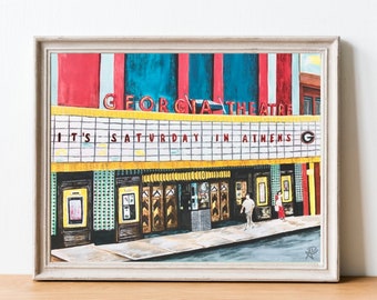 May include: A painting of a movie theater with the words "Georgia Theatre" and "It's Saturday in Athens" on the marquee. The building is painted in bright colors, including red, yellow, blue, and green. There are two people walking in front of the theater.