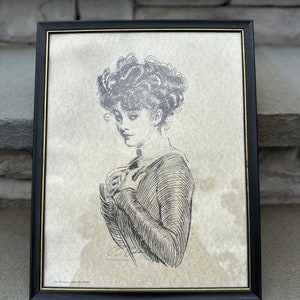 Vintage 1987 Grey Cloud Graphics 1909 Gibson Girl Framed Print 'Not Worrying about Her Rights' | Glass Cover & Black Plastic Frame