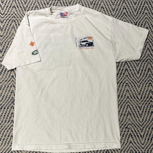 May include: Cream-coloured t-shirt with a Land Rover LR3 vehicle graphic on the front, with the text "LR3 - ENTIRELY NEW". The left sleeve has a Land Rover logo and a compass design. The shirt has a classic crew neck.