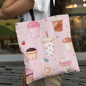 May include: A pink tote bag with a black handle and a repeating pattern of donuts, cupcakes, and coffee cups. The pattern is in a watercolor style.