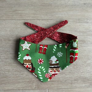 May include: Green bandana with a Christmas nutcracker and candy cane print. The bandana has a red glitter trim.