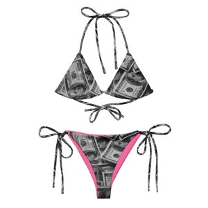 May include: A black and white bikini with a dollar bill print. The bikini top is a triangle style with adjustable straps. The bikini bottom is a cheeky style with adjustable ties on the sides.