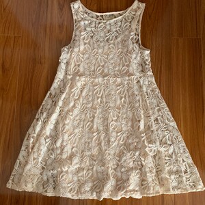 May include: A white lace dress with a sleeveless design and a floral pattern.