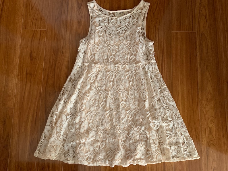 May include: A white lace dress with a sleeveless design and a floral pattern.