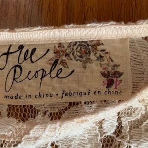 May include: A white lace top with a Free People tag that says "made in china - fabriqu&eacute; en chine" and has a floral design.