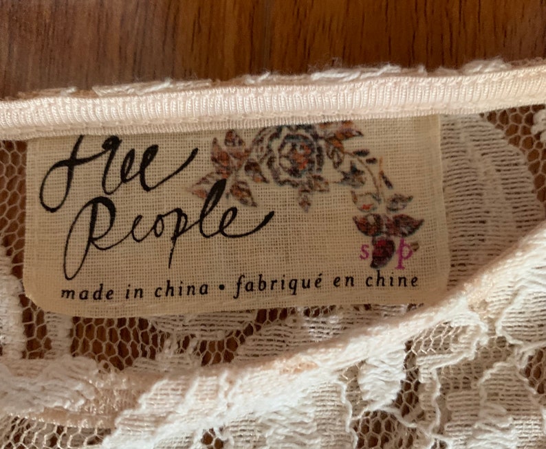 May include: A white lace top with a Free People tag that says "made in china - fabriqu&eacute; en chine" and has a floral design.