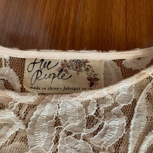 May include: A white lace top with a Free People label. The label says "Free People" and "made in china - fabriqu&eacute; en chine".