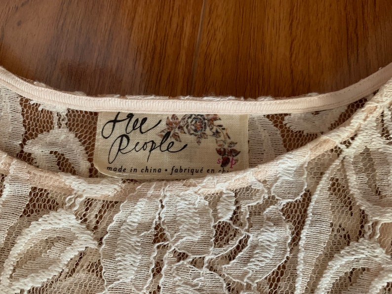 May include: A white lace top with a Free People label. The label says "Free People" and "made in china - fabriqu&eacute; en chine".