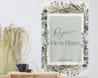 May include: A white banner with a green watercolor floral design. The banner has a light green rectangle in the center with the text "Rejoice He is Risen" and the scripture reference "Matthew 28:6".