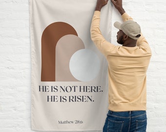 May include: A beige canvas wall tapestry with a brown, beige, and white abstract design. The tapestry has the text "He is not here. He is risen. Matthew 28:6" printed on it.