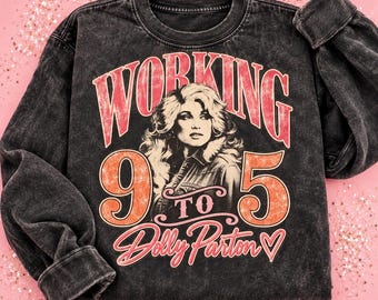 May include: A charcoal grey acid-wash crewneck sweatshirt featuring a graphic print of Dolly Parton. The text reads "WORKING 9 TO 5" in large red letters, with the number "9" and "5" in orange, and the name "Dolly Parton" in cursive script.