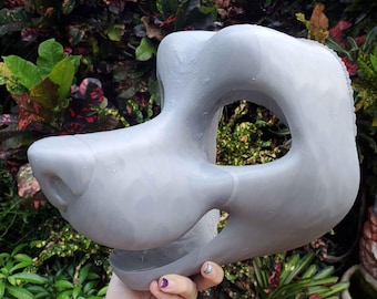 May include: A light grey, 3D-printed animal mask base featuring a smooth, rounded snout, large eye openings, and a curved jawline. The surface displays subtle horizontal layer lines characteristic of additive manufacturing, with a hollow interior.