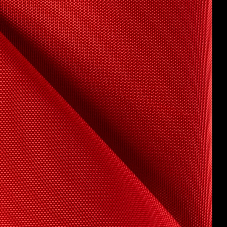 K&ouml;nnte beinhalten: Nahaufnahme eines leuchtend roten Stoffes mit einem strukturierten Webmuster. Das Material ist diagonal gefaltet, wodurch ein Spiel aus Licht und Schatten entsteht. Der Hintergrund ist einfarbig schwarz.