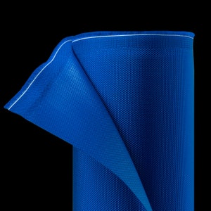 K&ouml;nnte beinhalten: Eine Rolle leuchtend blauen Stoffes mit strukturierter Oberfl&auml;che. Der Stoff ist teilweise abgerollt und zeigt einen wei&szlig; gen&auml;hten Rand. Der Hintergrund ist einfarbig schwarz und hebt die satte Farbe und Textur des Materials hervor.