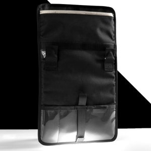 May include: Black messenger bag with a clear plastic pocket and multiple compartments. The bag has a zipper closure and a strap.