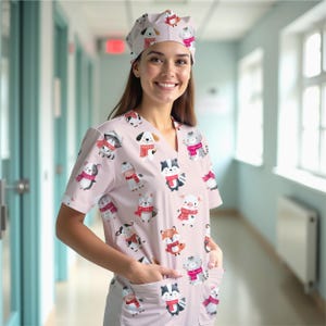 May include: A light pink medical scrub set with a repeating pattern of cartoon animals wearing scarves. The set includes a V-neck top with pockets and a matching cap. Animals include dogs, cats, raccoons, and pigs.