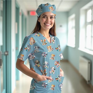 May include: A light blue medical scrub set featuring a repeating pattern of colorful, cartoon-style puppies. The set includes a V-neck top with pockets and a matching cap. The puppies are depicted in various poses and colors.
